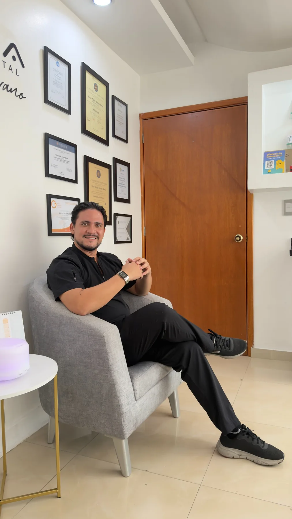 Dr. Óscar Serrano en el área de espera de su consultorio, junto a sus certificados de formación